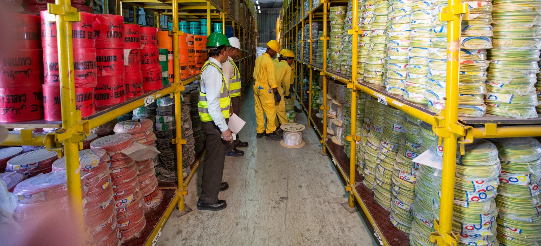 A supervisor with a clipboard checking a racked store while trade crews work behind him